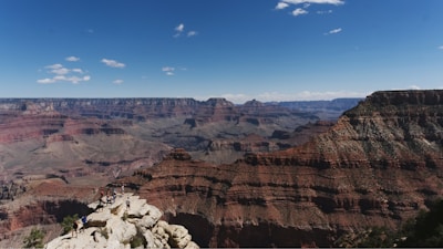 A group of happy French-speaking tourists admiring the vast expanse of the Grand Canyon at sunset.