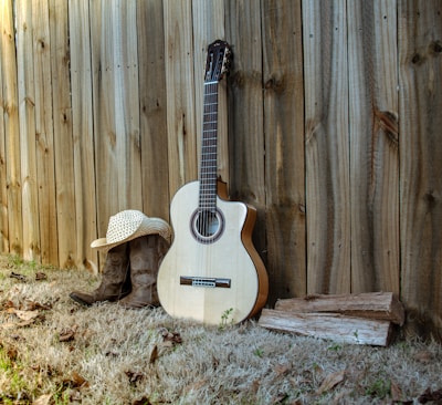 A country musician strumming a guitar beside a rustic wooden fence.
