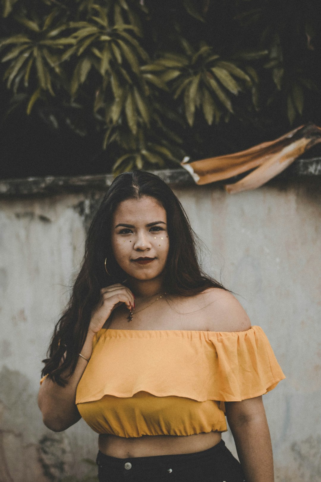 woman inn orange off-shoulder cropped top standing near wall