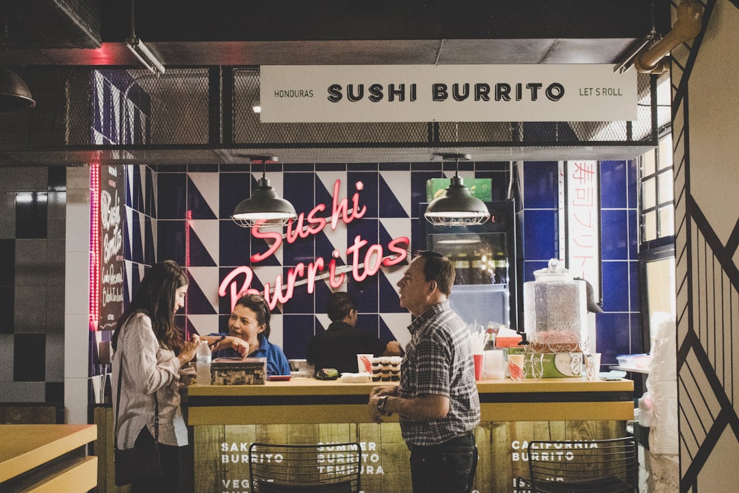 man standing in front of Sushi Burrito store