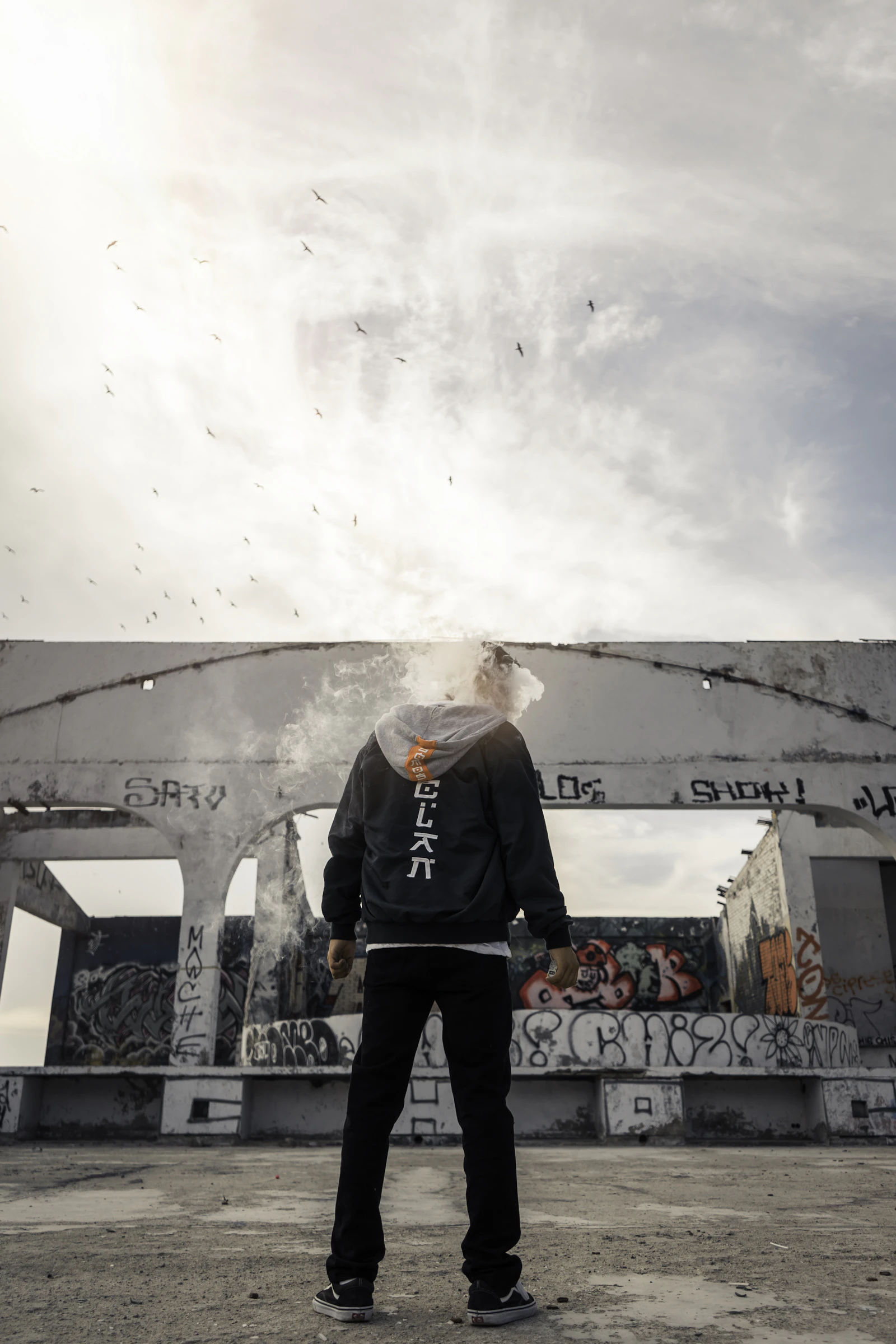 A headless person in a black hoodie standing near a concrete structure.
