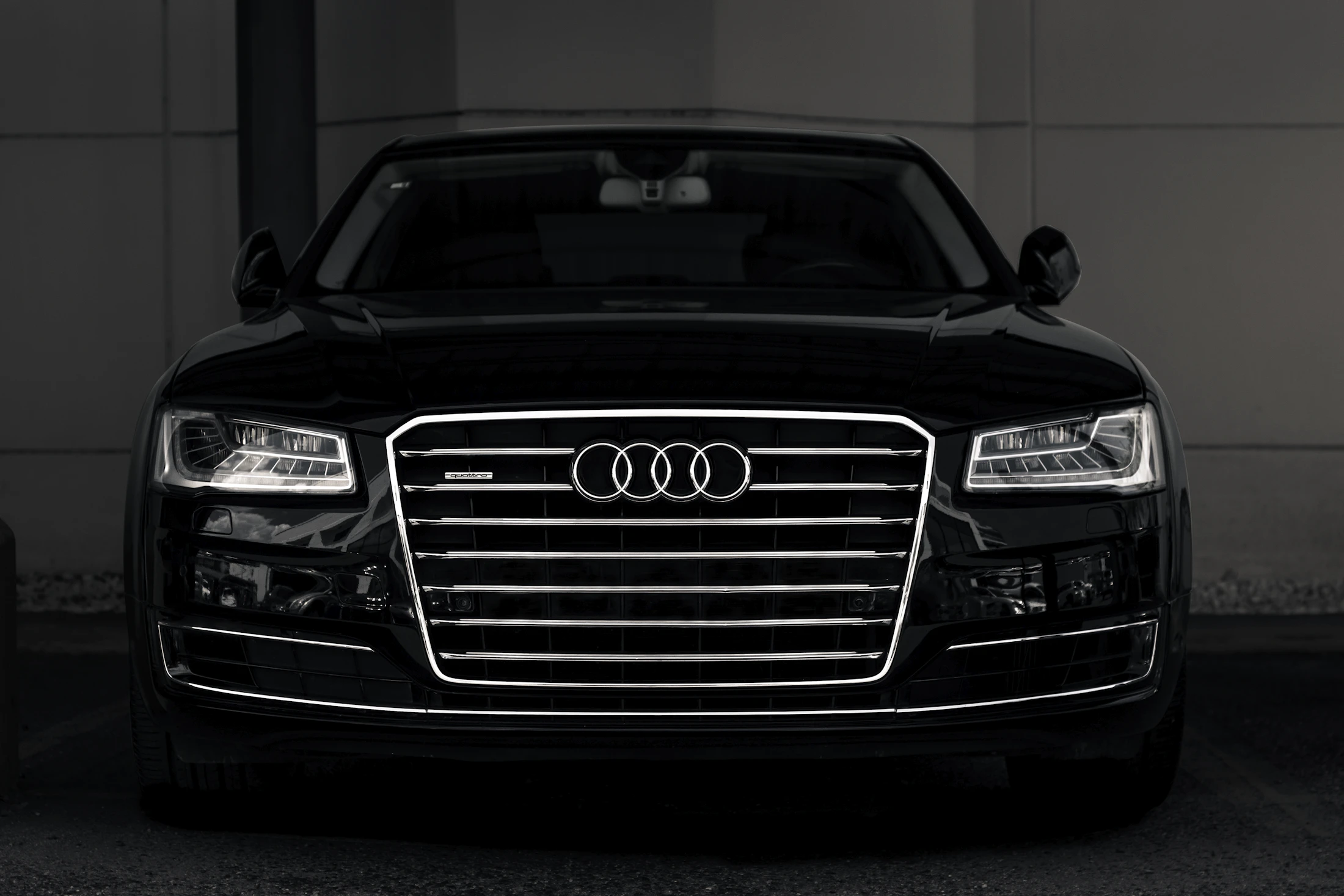 Black Audi A8 photographed head-on in low light, chrome Singleframe grille catching the light