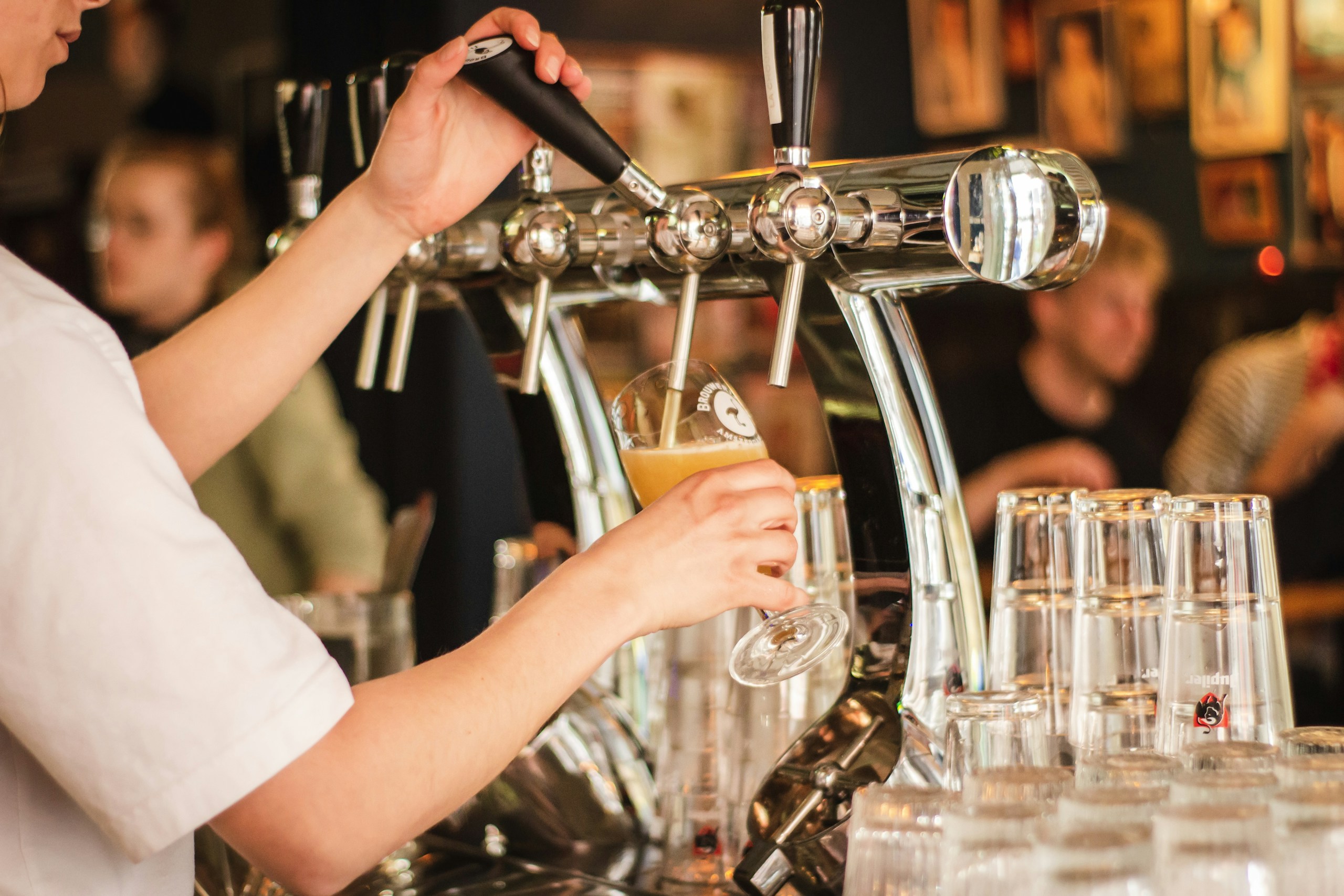 a photo of a person filling a glass from a beer tap