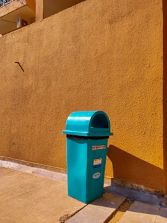 Close-up of a green HDPE Dalton trash bin with sturdy wheels on a clean hospital corridor