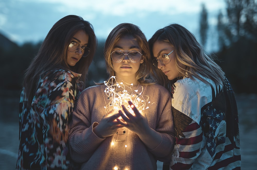 three women near string lights