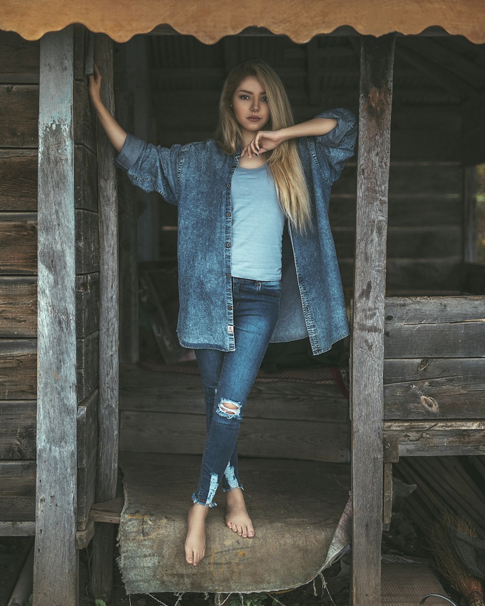 woman in denim jacket leaning on door frame