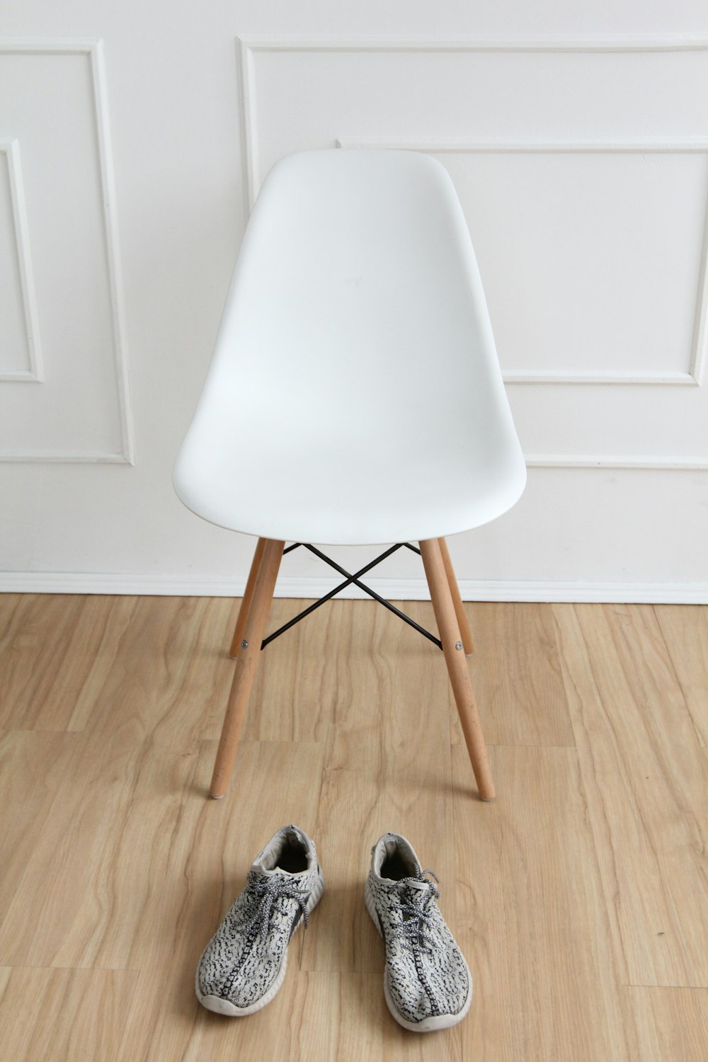 white and brown chair by wall and pair of shoes