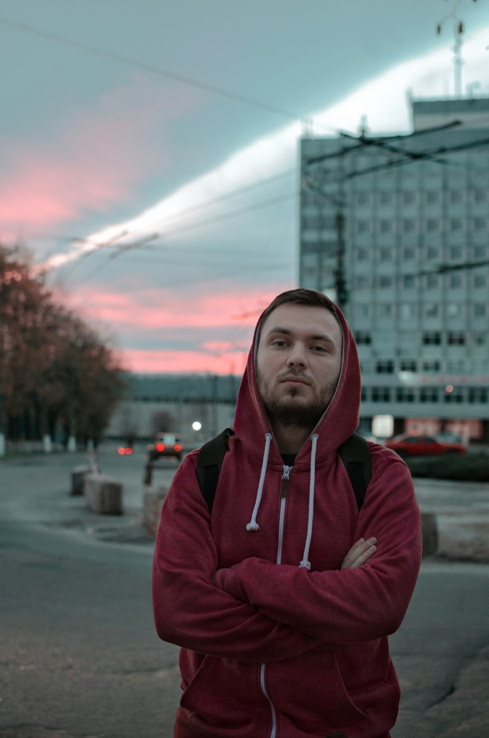 man in red hooded jacket standing outside during golden hoiur