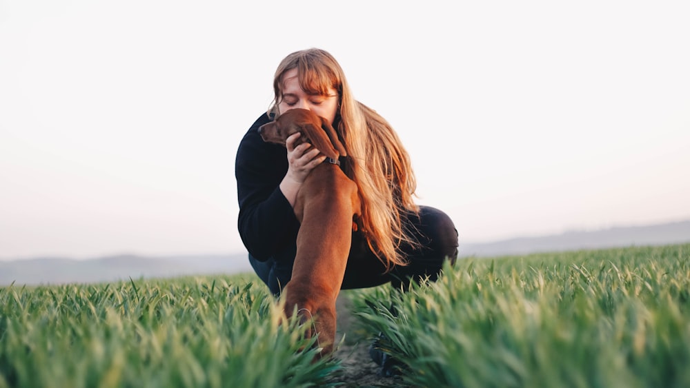 woman kissing adult brown dachshund