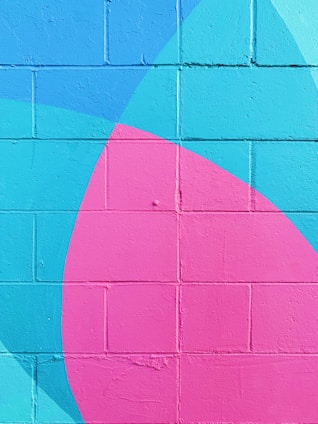 A vibrantly painted wall with geometric patterns in bright colors including pink and turquoise. The design features overlapping shapes, creating an abstract and modern look.