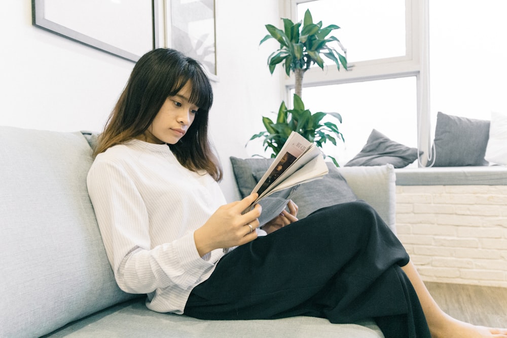 woman in white long-sleeved shirt and black skirt sitting on sofa