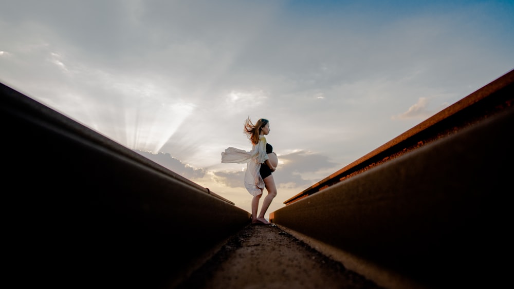 pregnant woman standing near rail while holding tummy