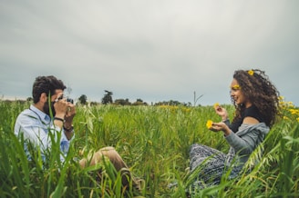 man taking photo of woman sitting on green grass