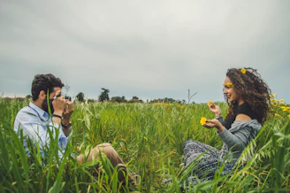man taking photo of woman sitting on green grass