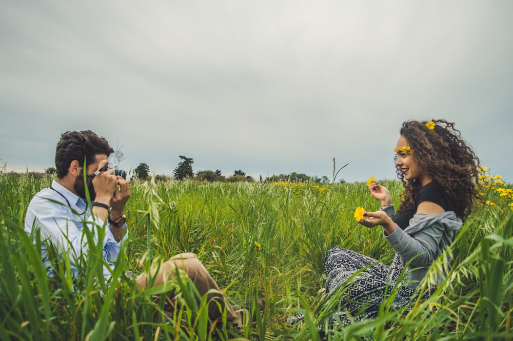 푸른 풀밭에 앉아있는 여자의 사진을 찍는 남자