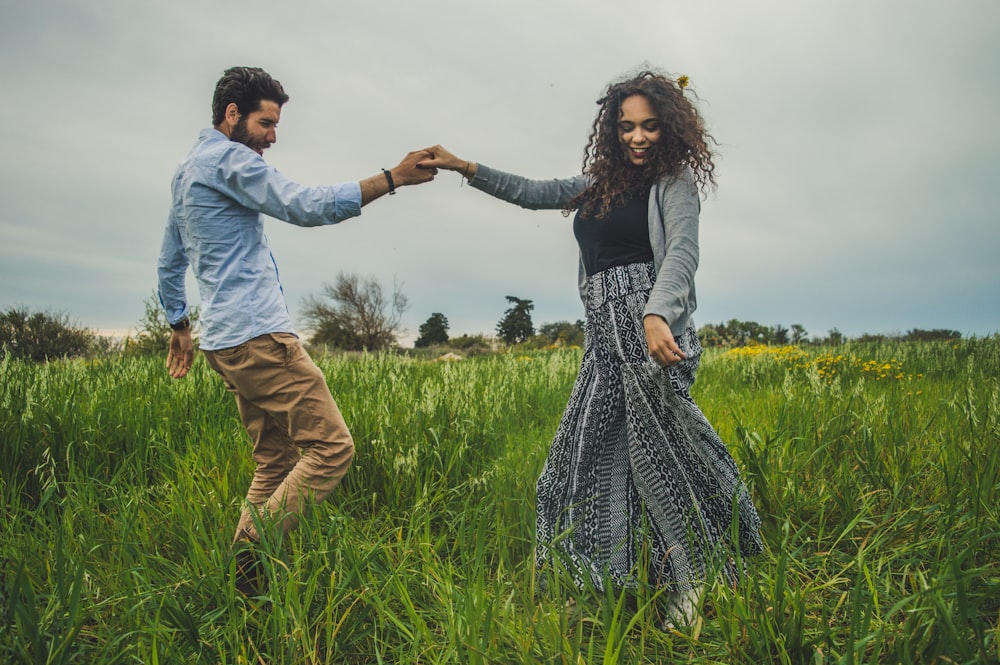 man and woman holding hands on green field