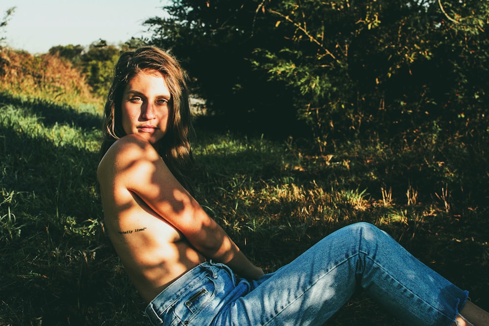 topless woman in blue jeans sitting on grass