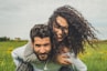 woman riding on man's back on green field