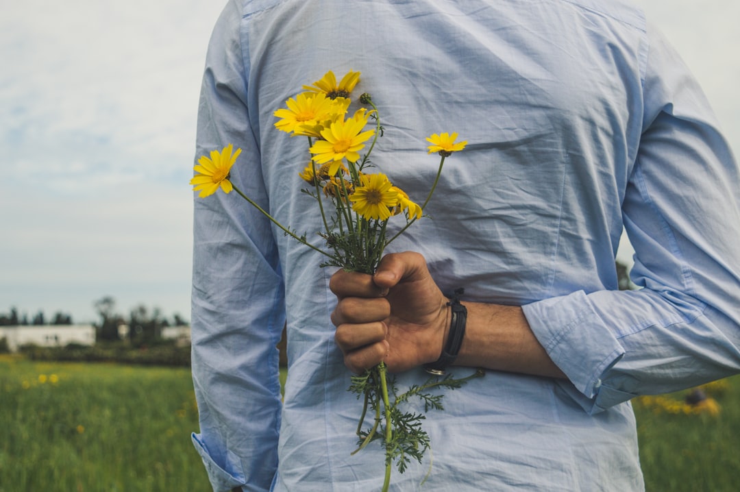 person holding yellow petaled flowers over his back