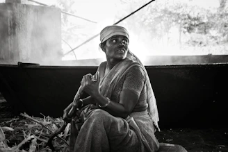 Traditional rural setup showing women carefully stirring jaggery mixture over a clay stove.
