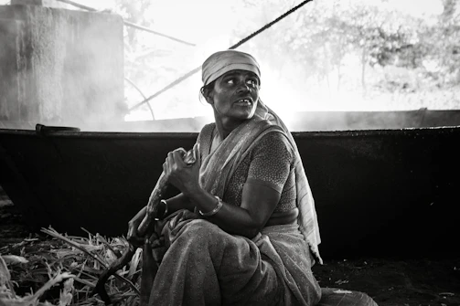 Traditional rural setup showing women carefully stirring jaggery mixture over a clay stove.