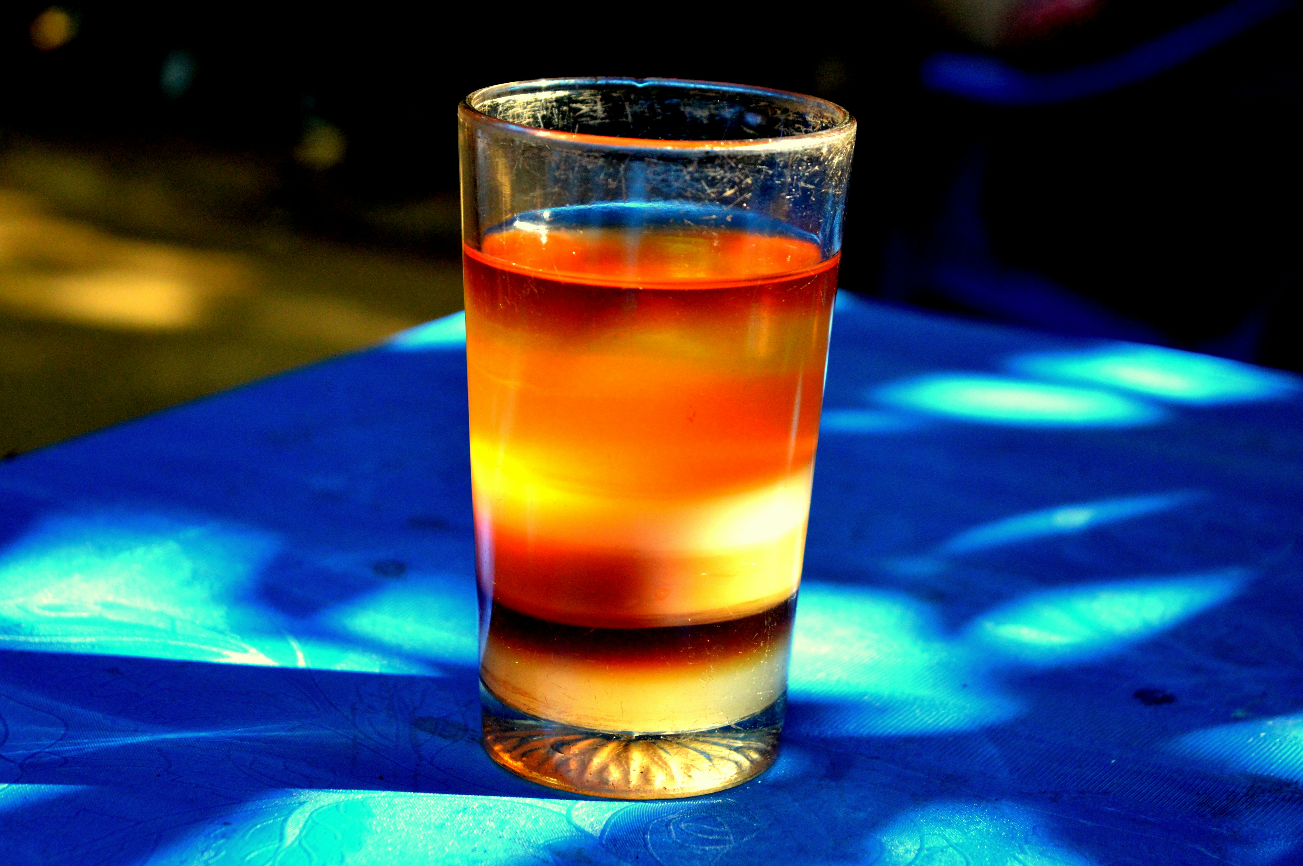 Deep blue layered cocktail in tall glass with citrus wheel, dark atmospheric background