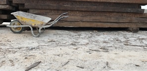 A rugged wheelbarrow filled with construction debris parked beside scaffolding poles.