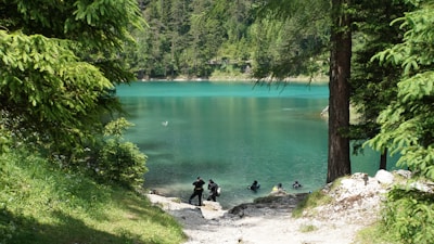 Wide shot of a peaceful lake surrounded by lush greenery with a diver preparing to enter the water