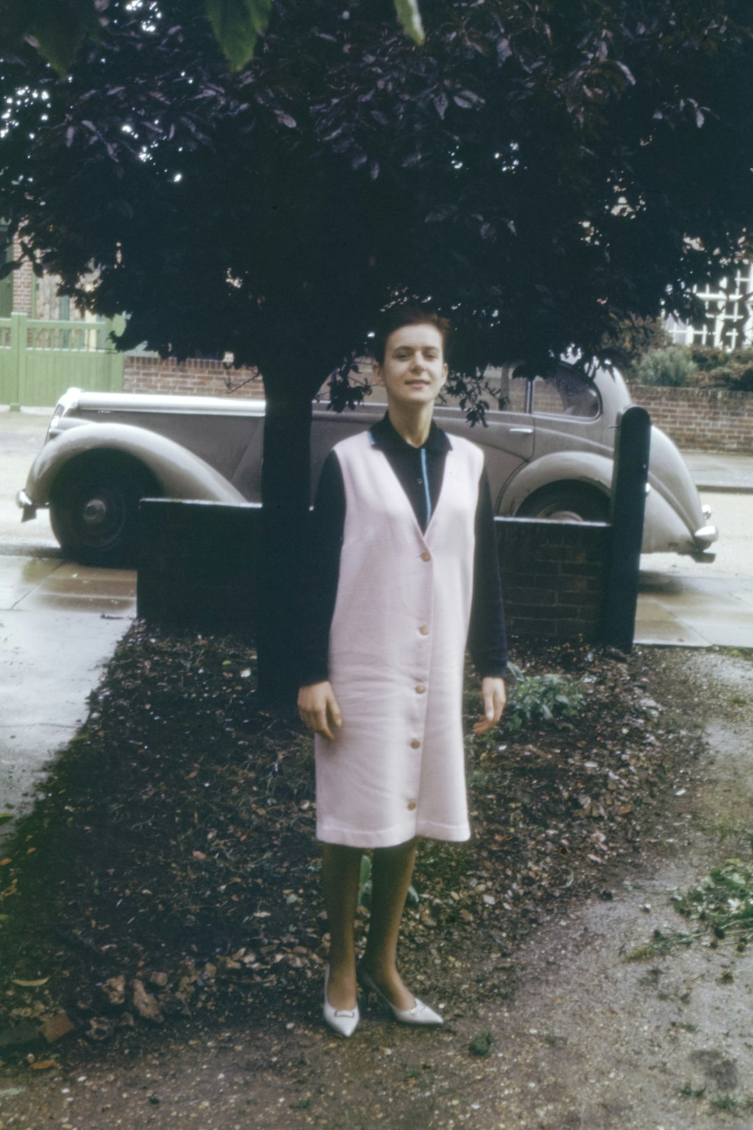 woman in white dress standing beside black car