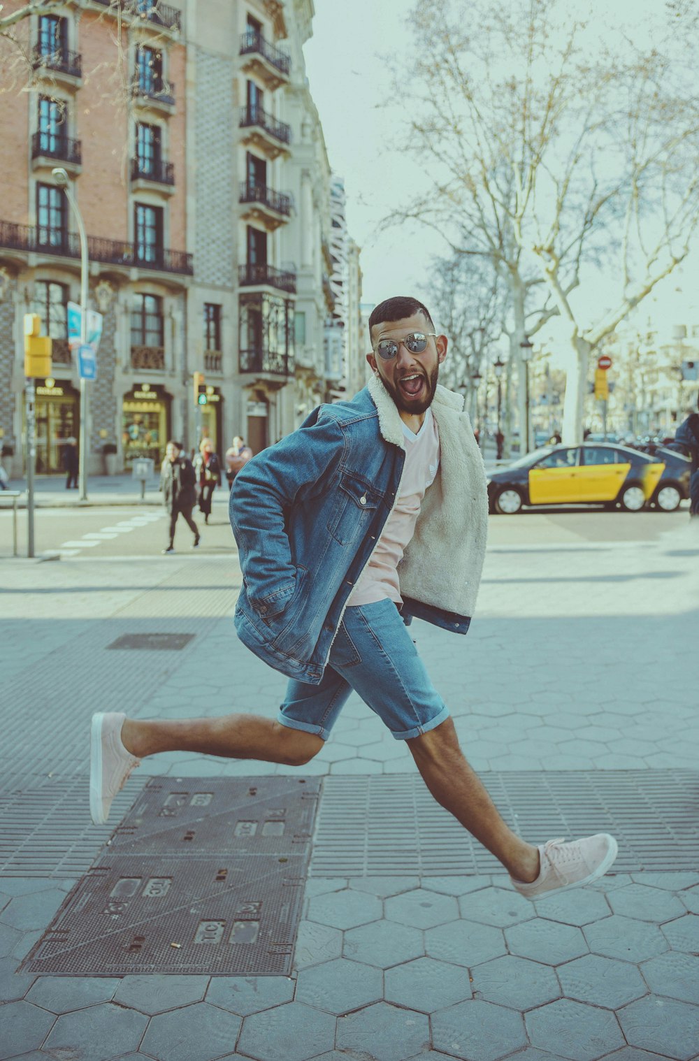 man in blue denim jacket and capris running on sidewalk during daytime