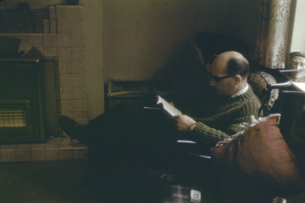 man sitting on sofa while reading book