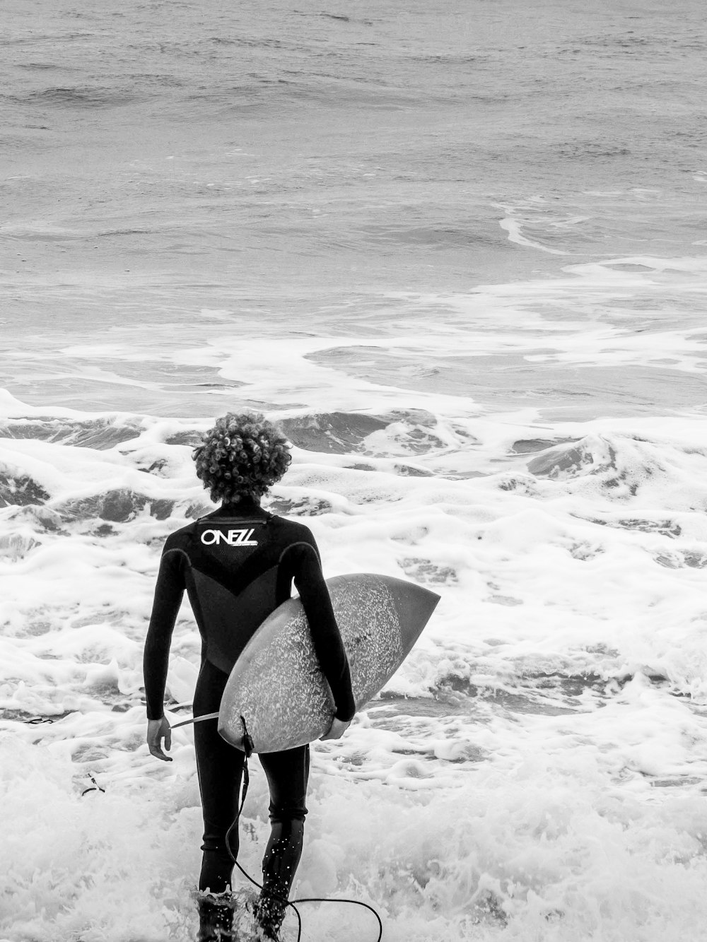 person wearing wet suit holding surfboard on seashore during daytime