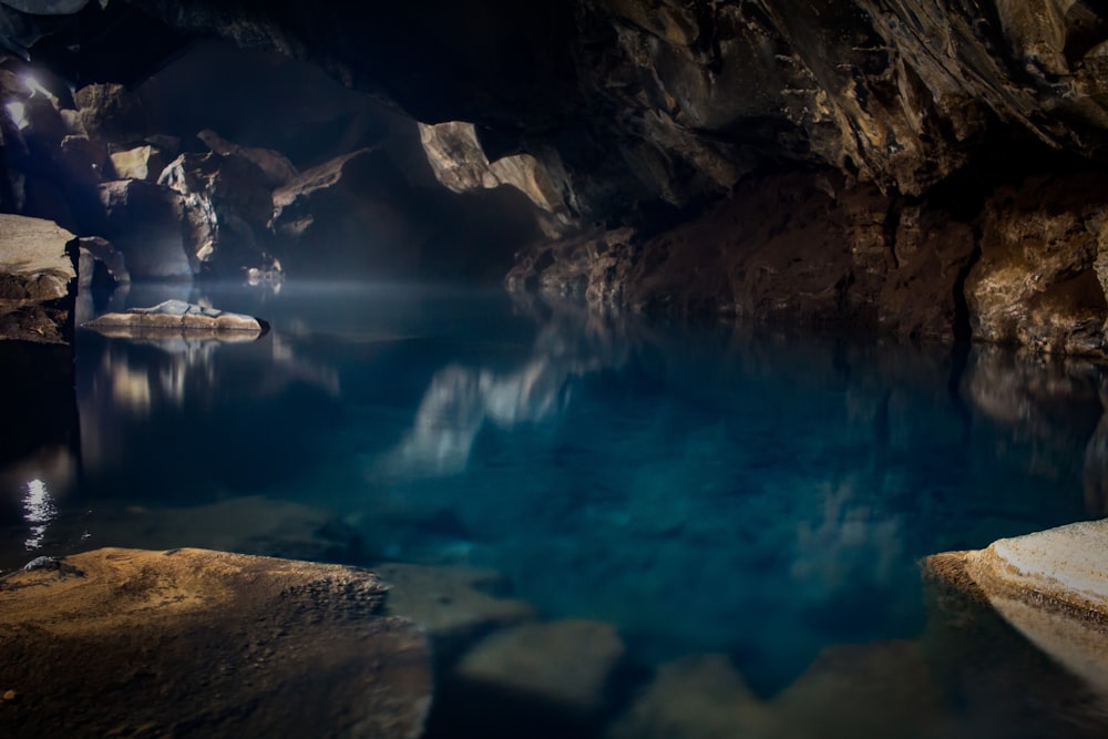 brown boat in body of water inside the cave