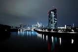 lighted high rise building near body of water at nighttime