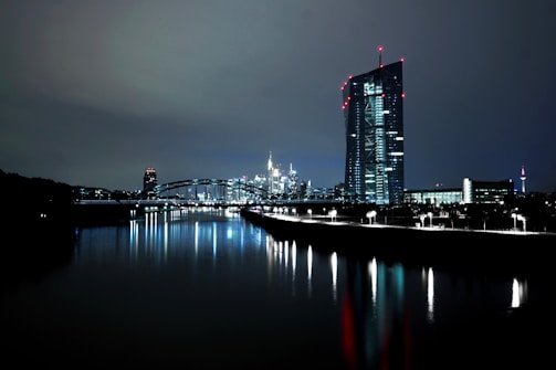 lighted high rise building near body of water at nighttime