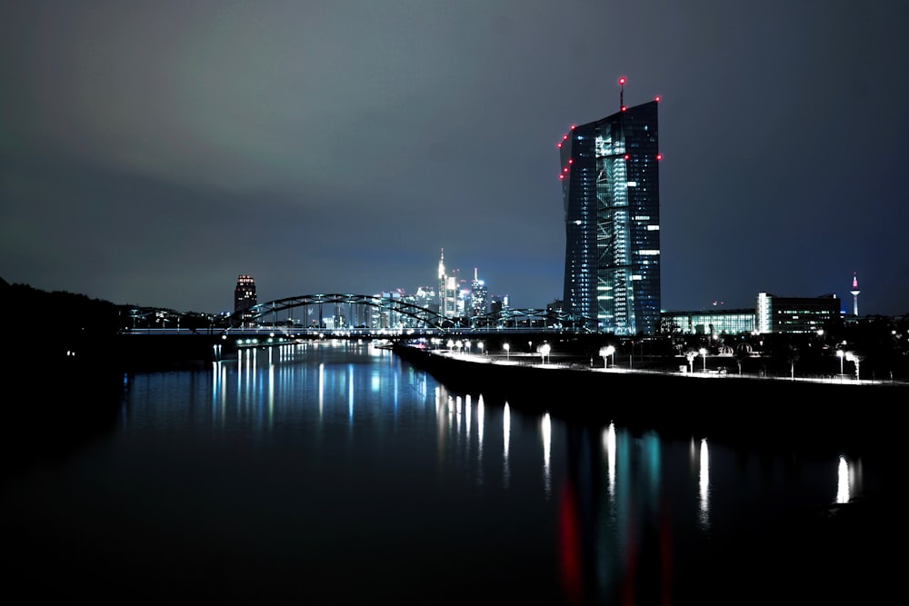 lighted high rise building near body of water at nighttime