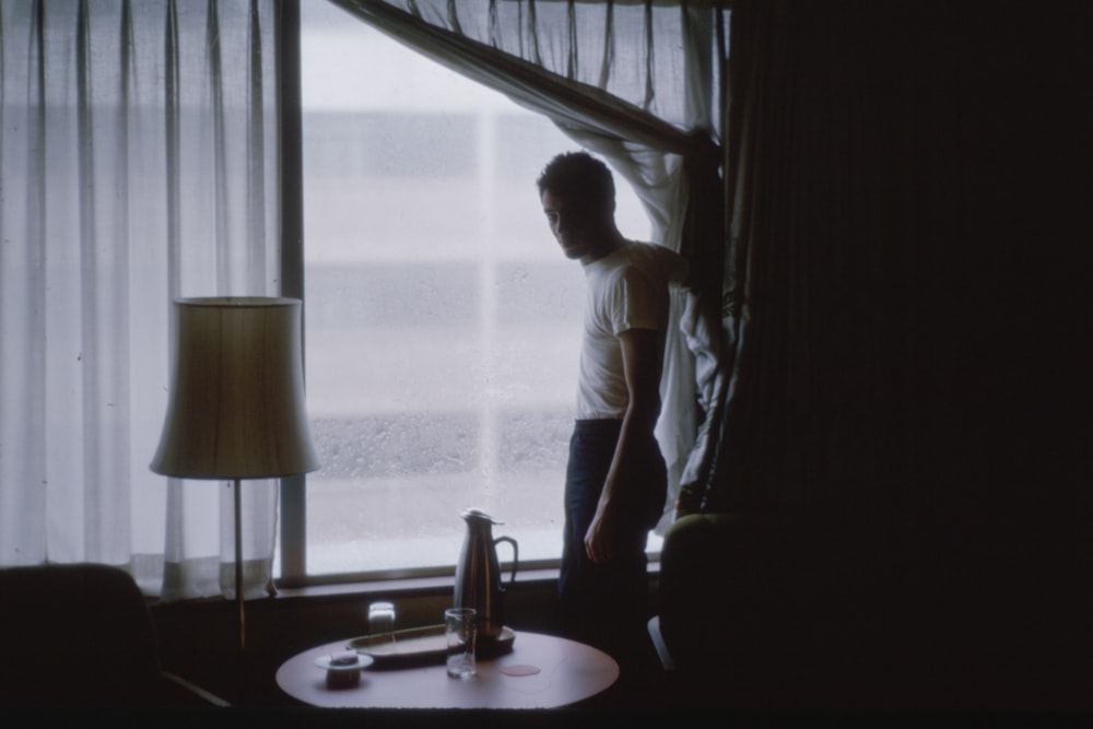 man standing by a glass window