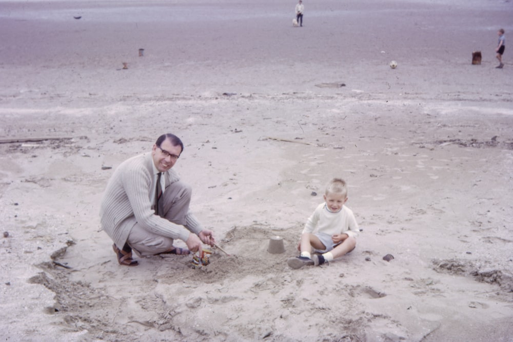 man playing sand beside boy