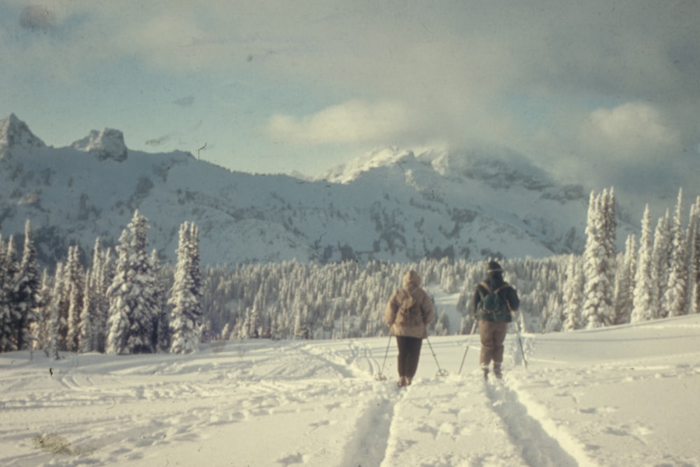 two people walking on snow field