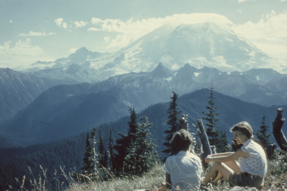 Due persone che si siedono sulla montagna sotto il cielo grigio