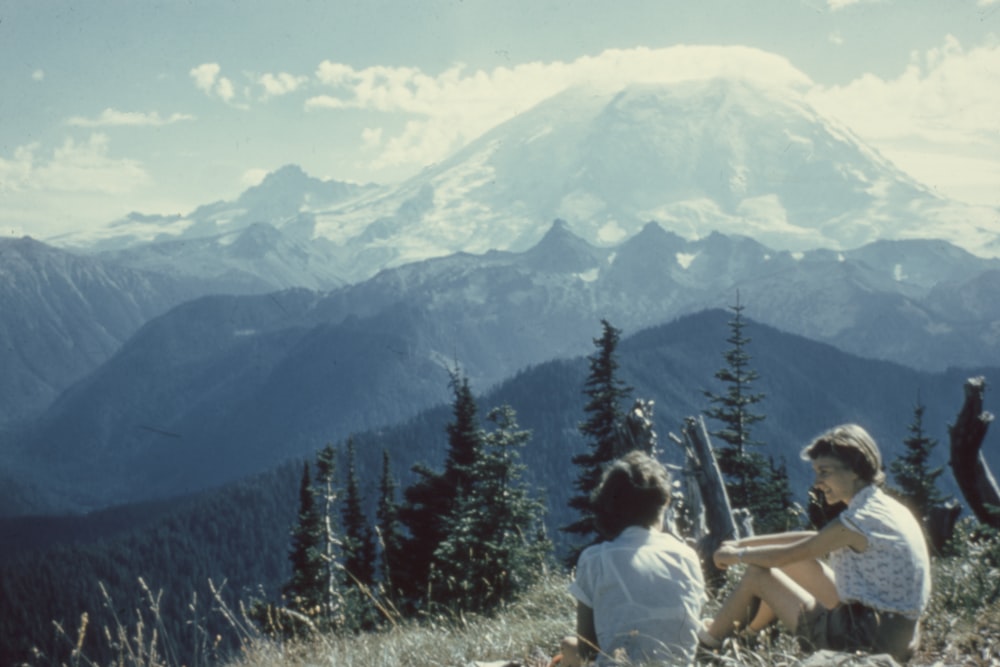 two people sitting on mountain under gray sky