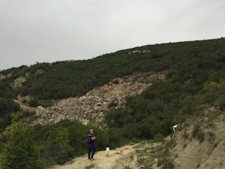 Anthony and Corrine hiking a forest trail with their German Shepherd.