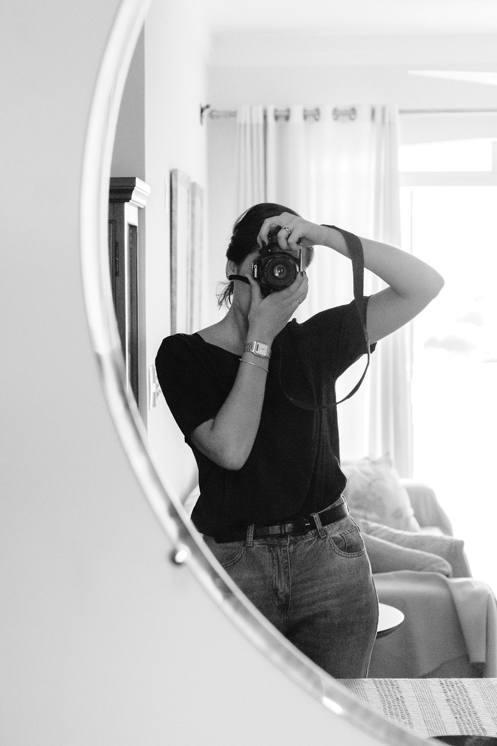 greyscale photo of woman taking photo on mirror