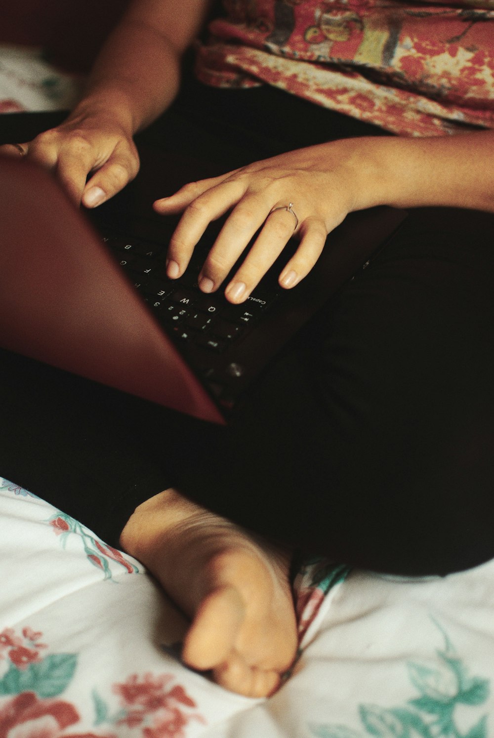 Persona sentada en la cama mientras usa la computadora portátil