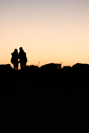An intimate moment between partners captured candidly against a charcoal-toned sunset.