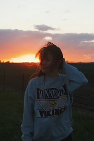 A person wearing a Lionsgear hoodie standing outdoors with a sunset backdrop.