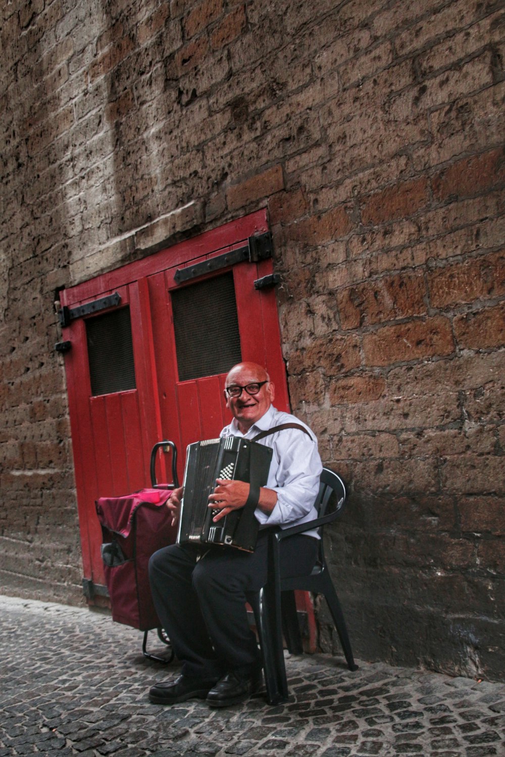 man sitting on black chair holding accordion