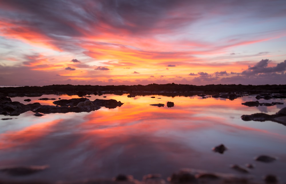 a sunset reflecting the sky and clouds over a body of water