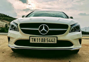 Front angle shot of a white Mercedes-Benz sedan under natural daylight.