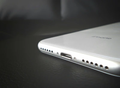 Modern iPhone charger with silver accents resting on a black textured surface